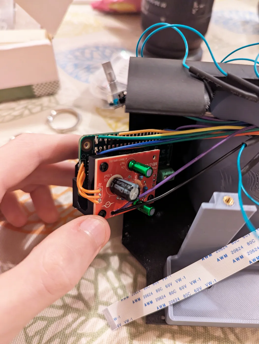 The red MB-272D board being fitted next to the Raspberry Pi Codec Zero inside the camera, with the mic wires running to it