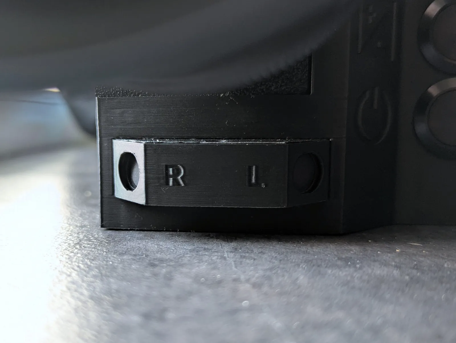 The mic housing from the side, low down on the front of the body next to the power button